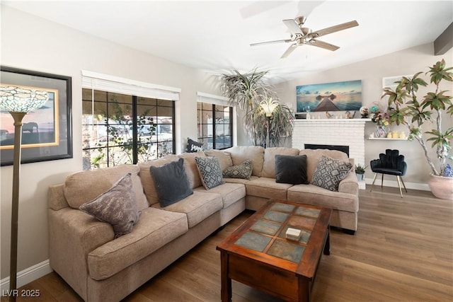 living area with a brick fireplace, baseboards, and wood finished floors