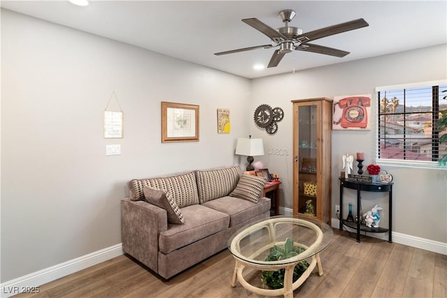 living room featuring ceiling fan, baseboards, and wood finished floors