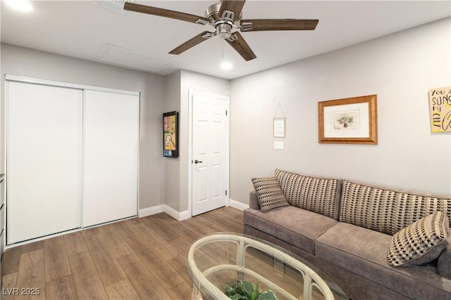 living room featuring wood finished floors, a ceiling fan, and baseboards