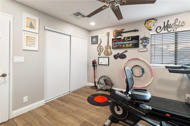 exercise room featuring a ceiling fan, baseboards, visible vents, and wood finished floors