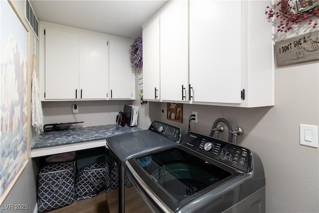 clothes washing area featuring cabinet space, washing machine and dryer, visible vents, and wood finished floors