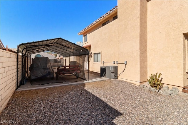 exterior space featuring a patio, fence, central AC, and a detached carport