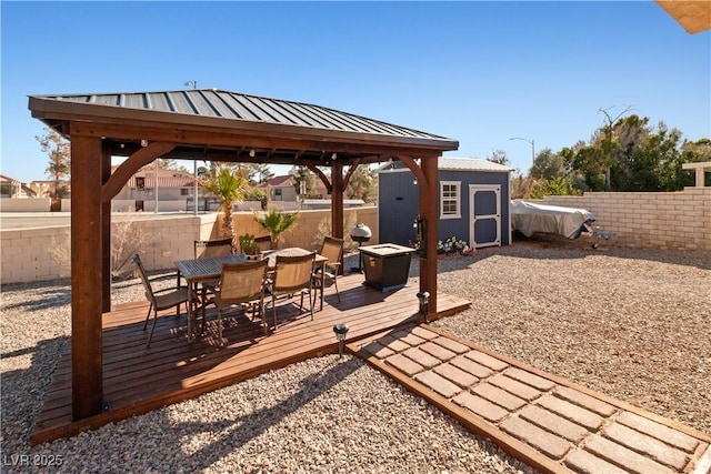 view of patio / terrace featuring an outbuilding, a deck, a fenced backyard, a storage unit, and outdoor dining space