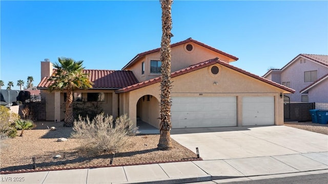 mediterranean / spanish-style house with a garage, concrete driveway, a tile roof, and stucco siding