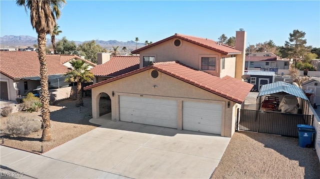 mediterranean / spanish home with concrete driveway, an attached garage, a mountain view, and stucco siding