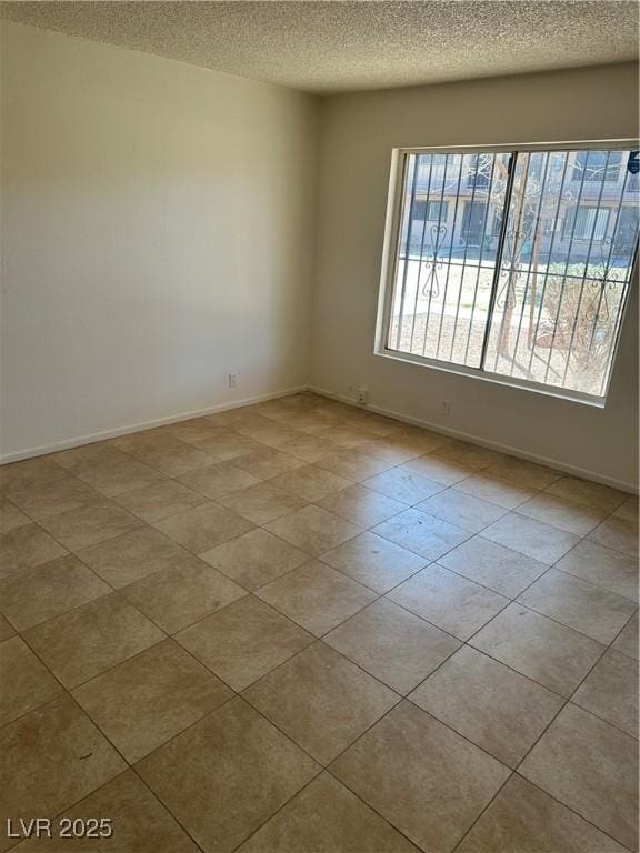 unfurnished room featuring a textured ceiling and baseboards