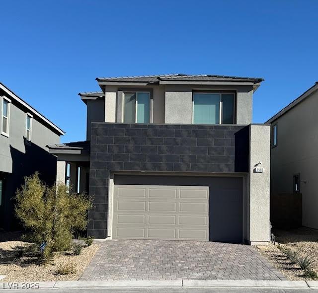 view of front facade with a garage, decorative driveway, and stucco siding