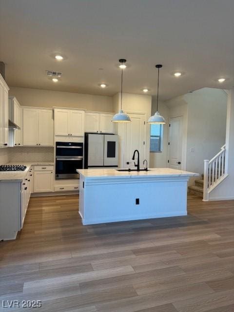 kitchen featuring dobule oven black, wood finished floors, stovetop, smart refrigerator, and a sink