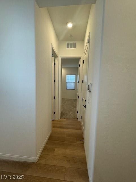 corridor featuring light wood-style floors, visible vents, and baseboards