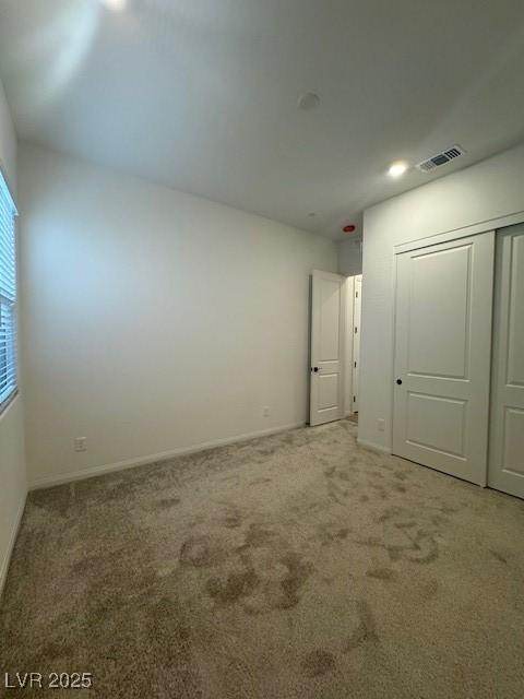 unfurnished bedroom with baseboards, a closet, visible vents, and carpet flooring