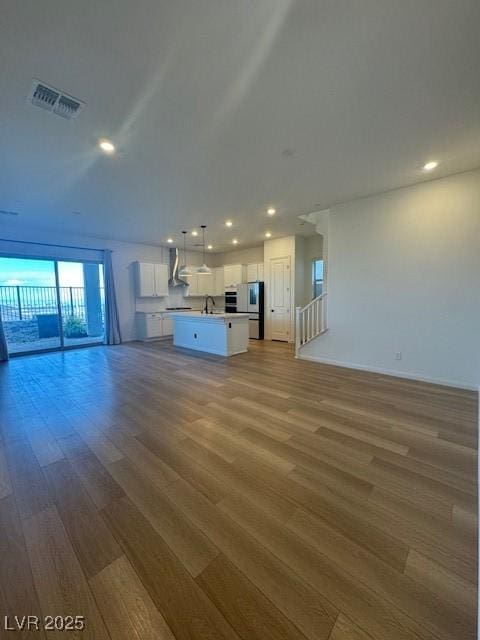 unfurnished living room featuring wood finished floors, visible vents, and recessed lighting