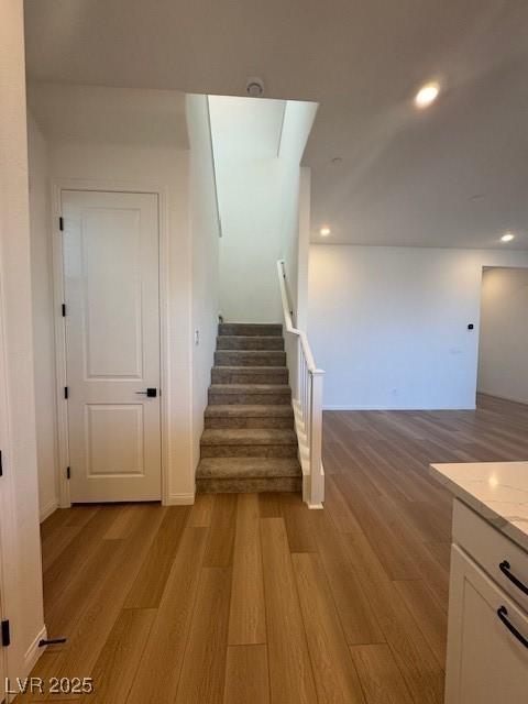 staircase with wood finished floors and recessed lighting