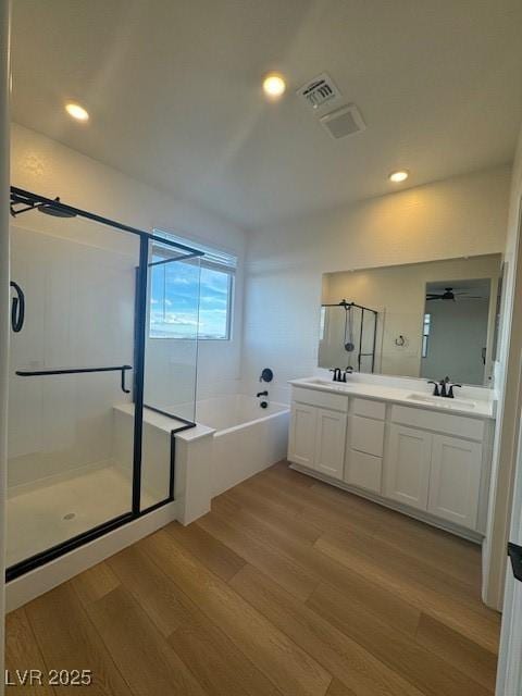 full bathroom featuring double vanity, wood finished floors, and a shower stall