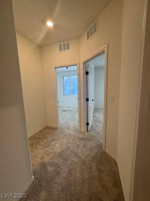 hall featuring baseboards, visible vents, and carpet flooring