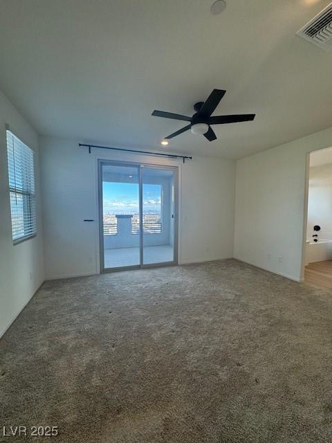 carpeted spare room with visible vents and ceiling fan