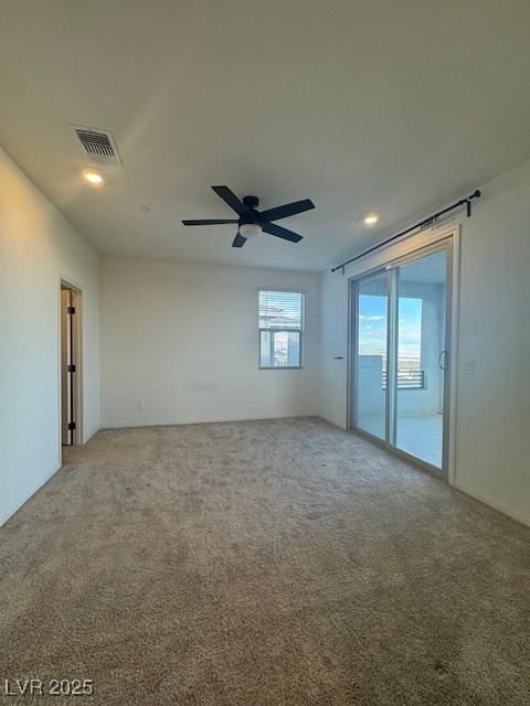 carpeted spare room featuring ceiling fan and visible vents