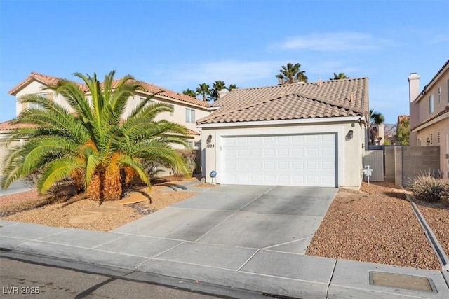 mediterranean / spanish-style house featuring a tile roof, stucco siding, an attached garage, fence, and driveway