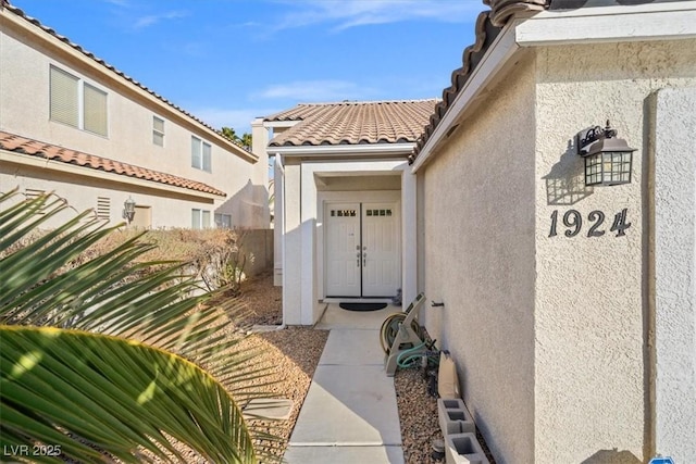 entrance to property featuring a tile roof and stucco siding