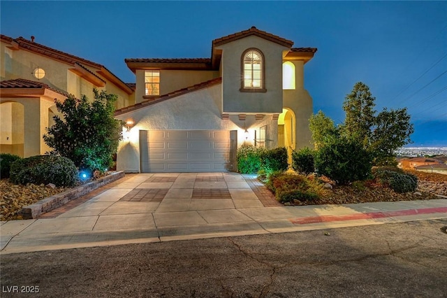 mediterranean / spanish house featuring concrete driveway, an attached garage, and stucco siding