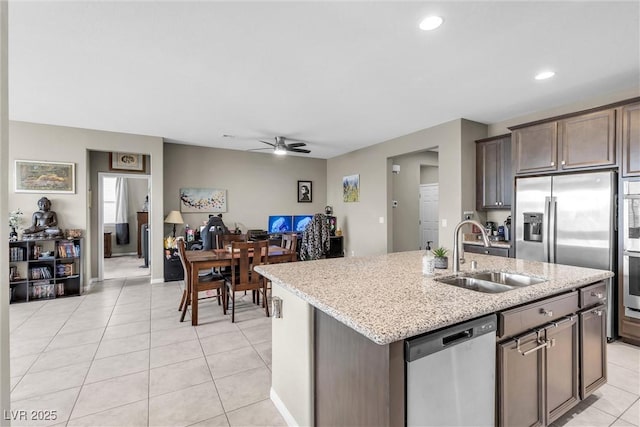 kitchen with a center island with sink, light tile patterned floors, appliances with stainless steel finishes, a ceiling fan, and a sink