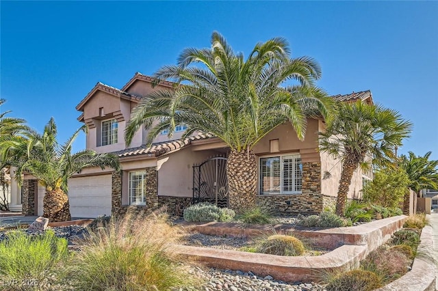 mediterranean / spanish home with stone siding, an attached garage, and stucco siding