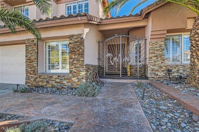 entrance to property featuring stone siding, a tile roof, a gate, and stucco siding