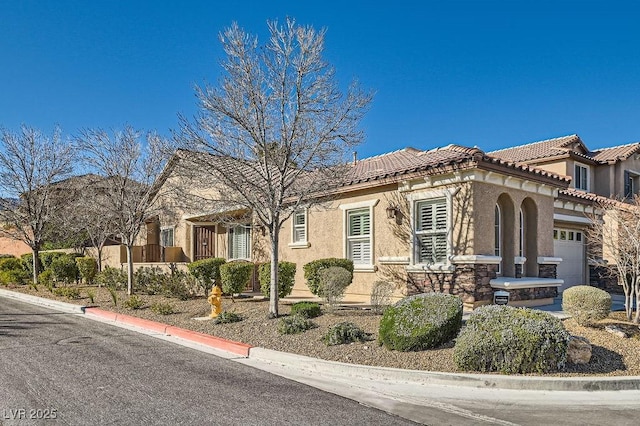 view of front of house featuring a garage, a tile roof, and stucco siding