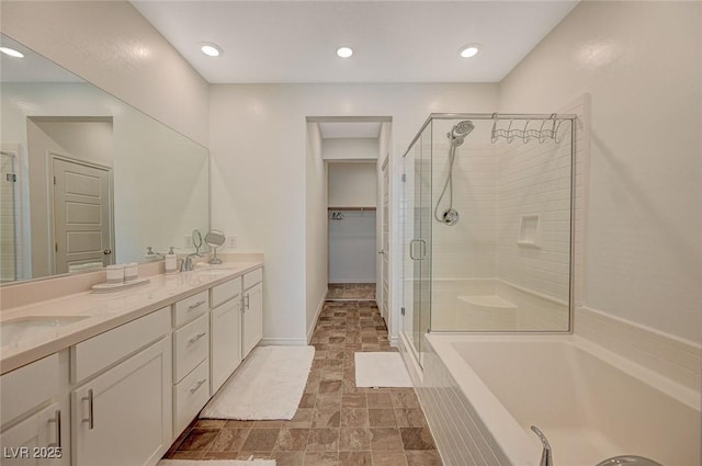 full bathroom featuring a stall shower, a sink, and a walk in closet