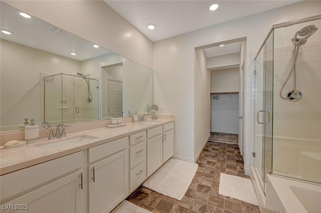 full bath with a stall shower, a walk in closet, a sink, and double vanity