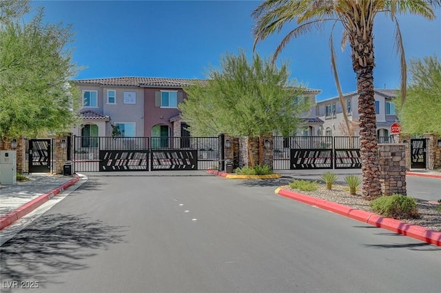 view of street featuring a residential view, a gate, a gated entry, and curbs