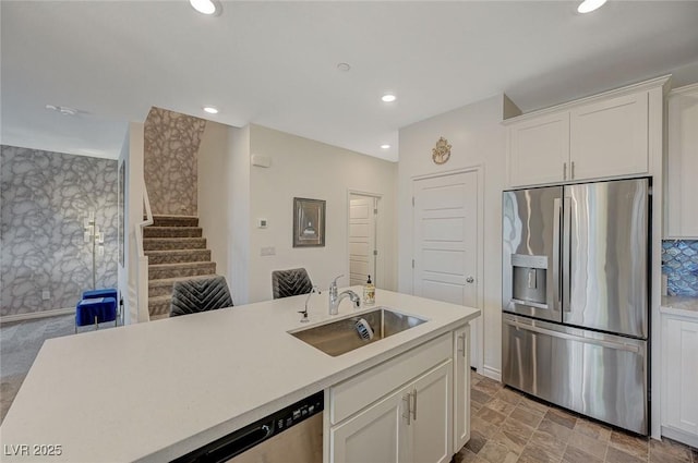 kitchen with appliances with stainless steel finishes, light countertops, white cabinetry, a sink, and recessed lighting