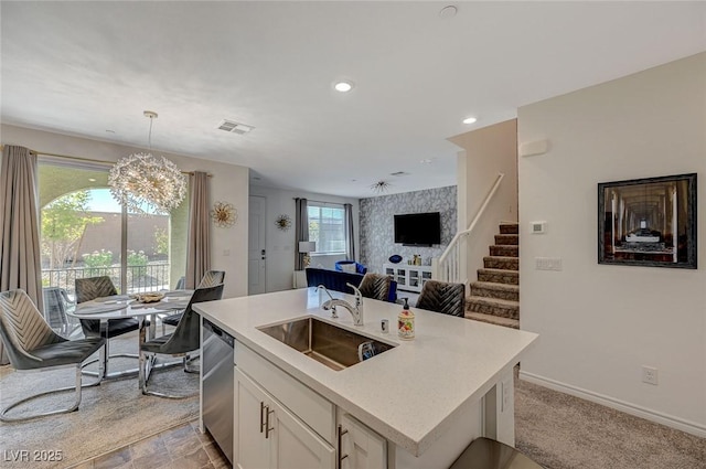 kitchen with a sink, visible vents, white cabinets, open floor plan, and dishwasher