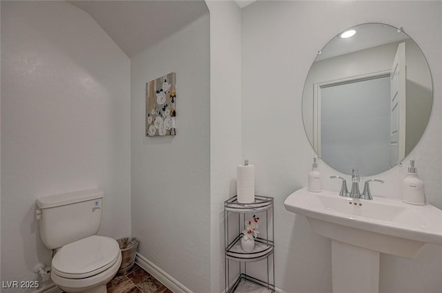 half bath featuring baseboards, a sink, and toilet