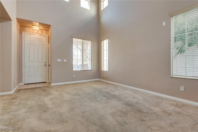 entrance foyer with baseboards, light colored carpet, plenty of natural light, and a high ceiling