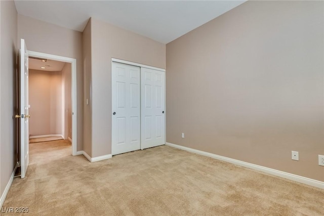 unfurnished bedroom with baseboards, a closet, and light colored carpet