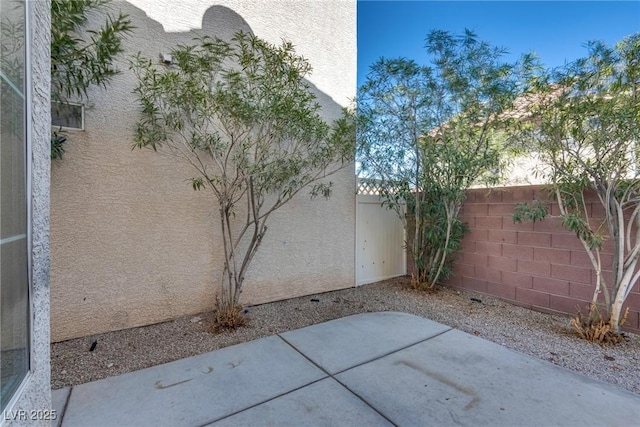 exterior space featuring a patio area, fence, and stucco siding