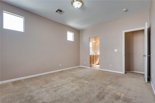 unfurnished bedroom with baseboards, ensuite bathroom, visible vents, and light colored carpet