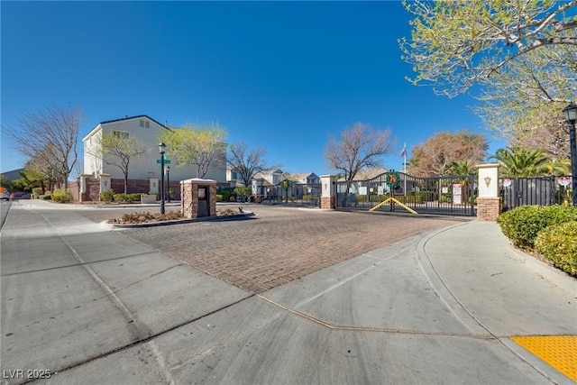 view of street with street lights, a gated entry, a residential view, a gate, and traffic signs