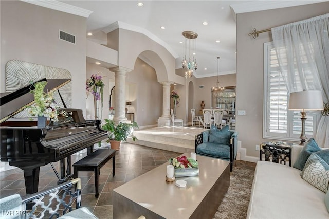 living area with arched walkways, a notable chandelier, visible vents, ornate columns, and crown molding