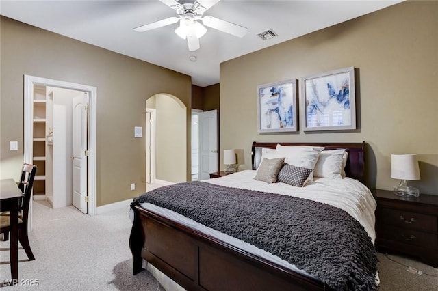 bedroom featuring arched walkways, visible vents, a ceiling fan, light carpet, and baseboards