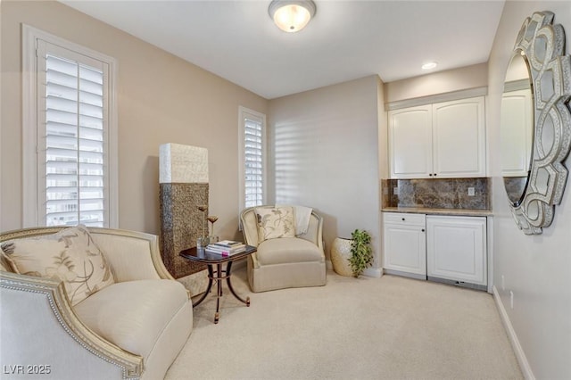 living area featuring baseboards and light colored carpet