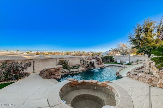 view of pool featuring a water slide, a fenced backyard, and a pool with connected hot tub