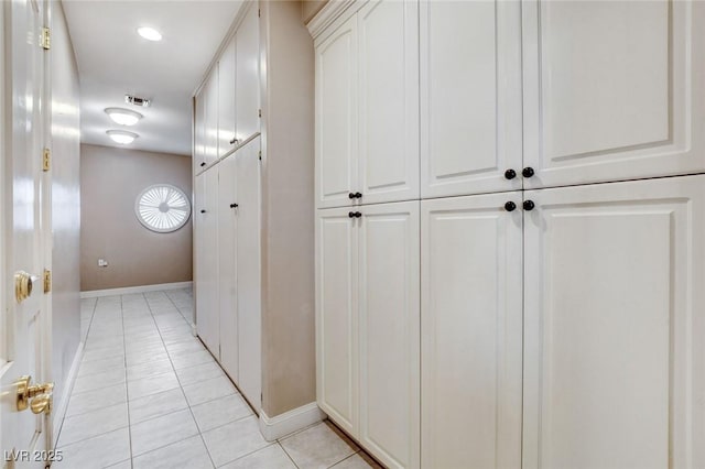 corridor with light tile patterned floors, baseboards, and visible vents