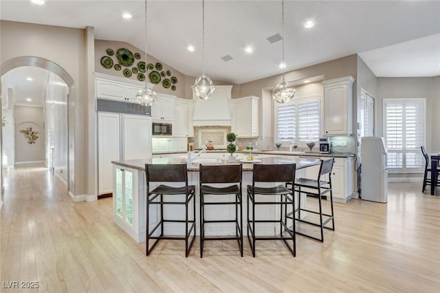 kitchen with arched walkways, a kitchen island, a breakfast bar area, and built in appliances