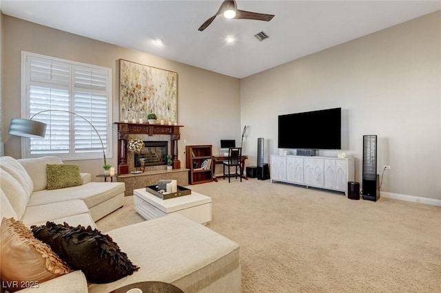 living area with light colored carpet, visible vents, a fireplace, and ceiling fan