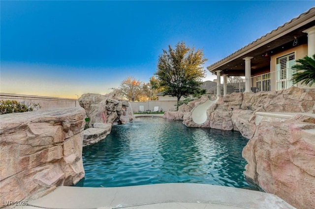 view of swimming pool with a water slide, a fenced backyard, and a fenced in pool