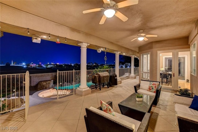 patio at night with an outdoor hangout area, fence, and a ceiling fan