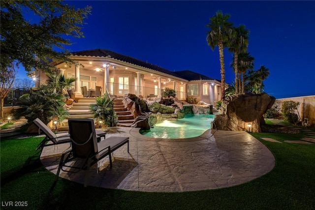 back of house at twilight featuring a tiled roof, stairs, an outdoor pool, and a patio