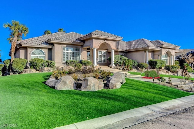 view of front of home with a tiled roof, a front lawn, and stucco siding