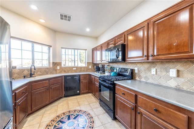 kitchen with light tile patterned flooring, a sink, visible vents, decorative backsplash, and black appliances